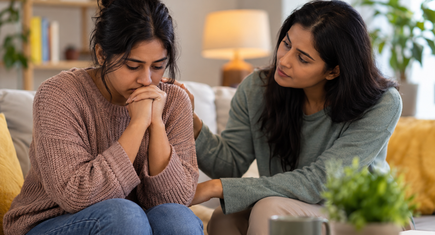 Two friends sitting closely together having a supportive conversation about mental health.