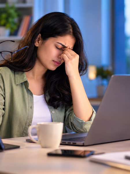 Woman experiencing digital eye strain while using a laptop